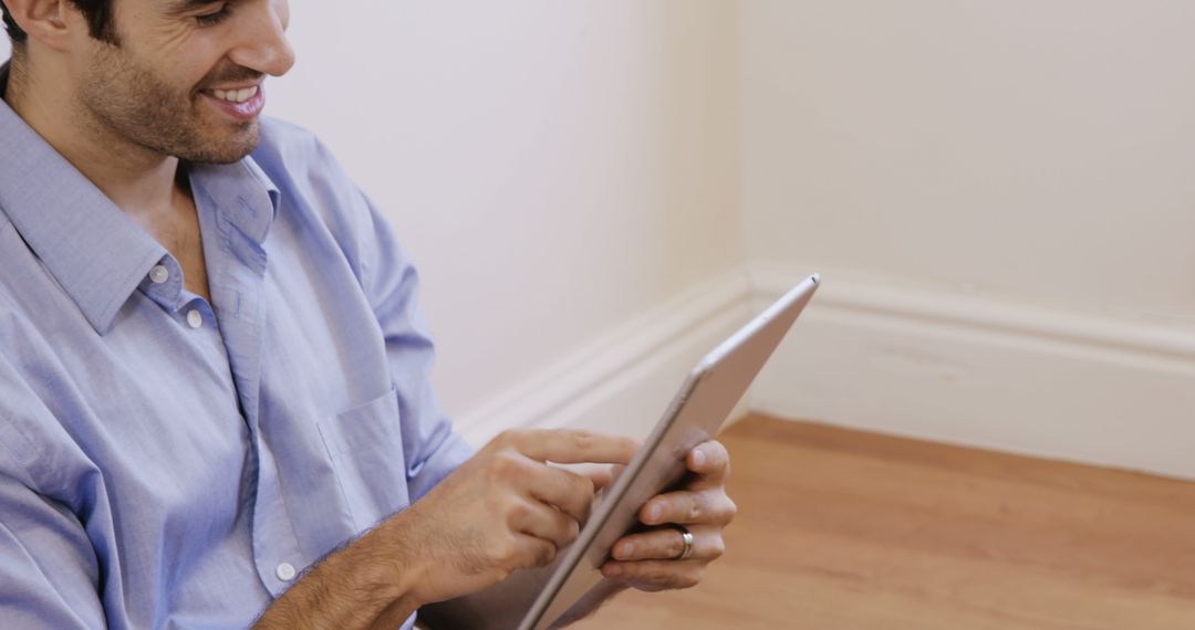 Man Using Tablet While Sitting on Floor Smiling - Free Images, Stock Photos and Pictures on Pikwizard.com