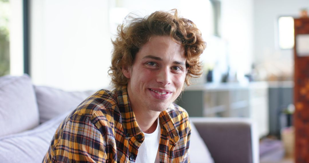 Smiling Young Man with Curly Hair Relaxing at Home - Free Images, Stock Photos and Pictures on Pikwizard.com