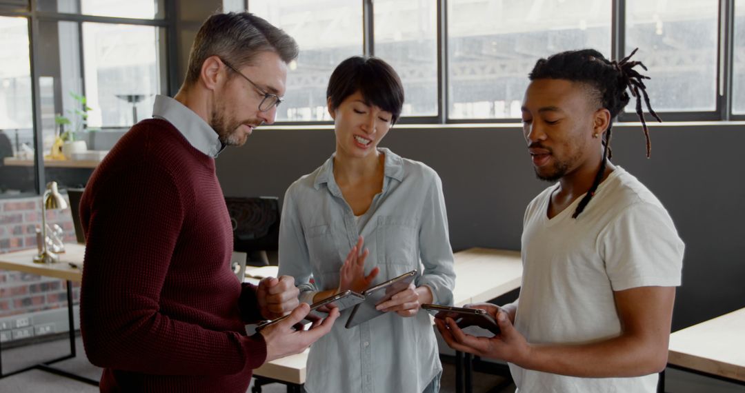 Team Collaborating with Technology Gadgets in Modern Office