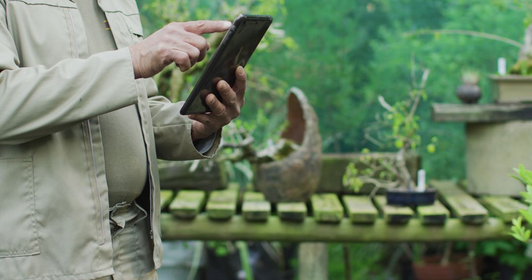 Gardener Using Digital Tablet in Lush Garden - Free Images, Stock Photos and Pictures on Pikwizard.com