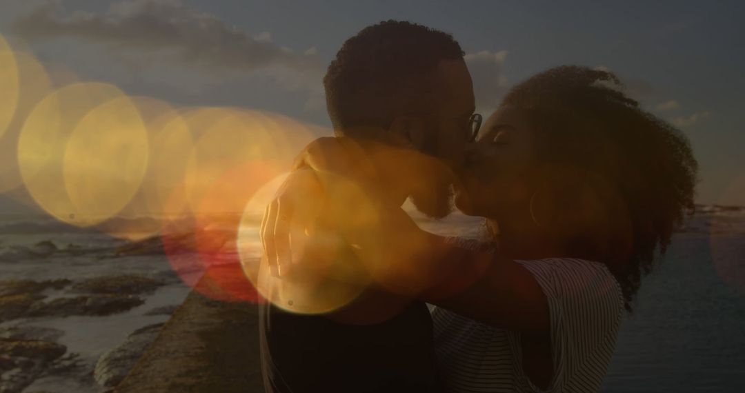Image of lens flares over diverse couple kissing and hugging on beach against sea and sky - Free Images, Stock Photos and Pictures on Pikwizard.com