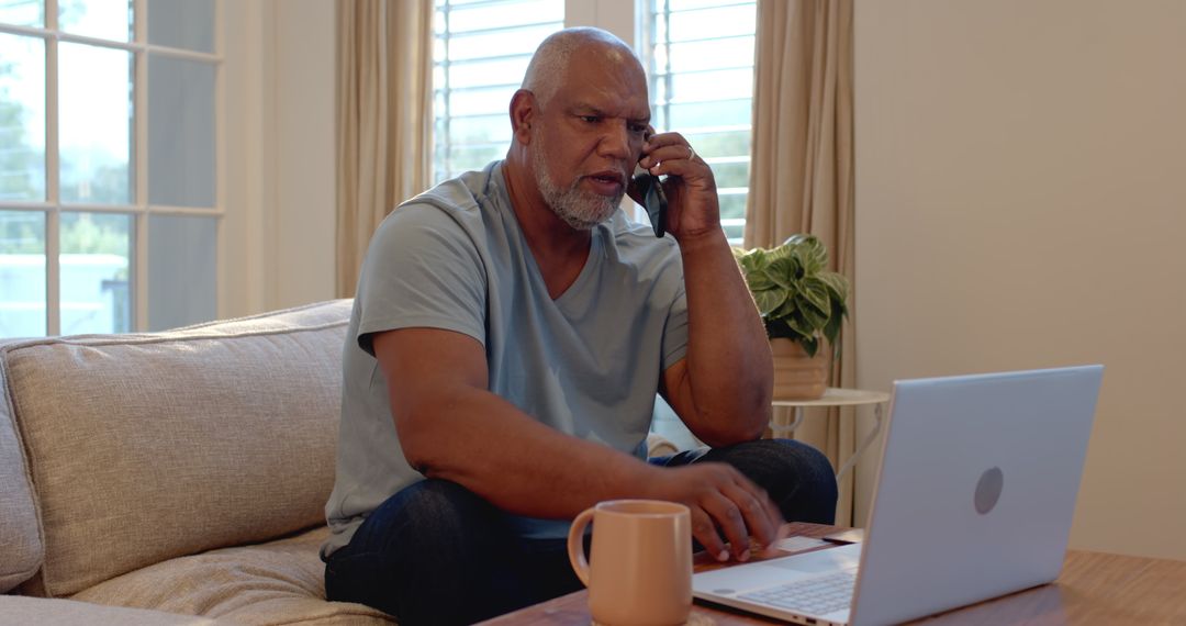 Senior Man Enjoying Conversation on Phone and Laptop at Home