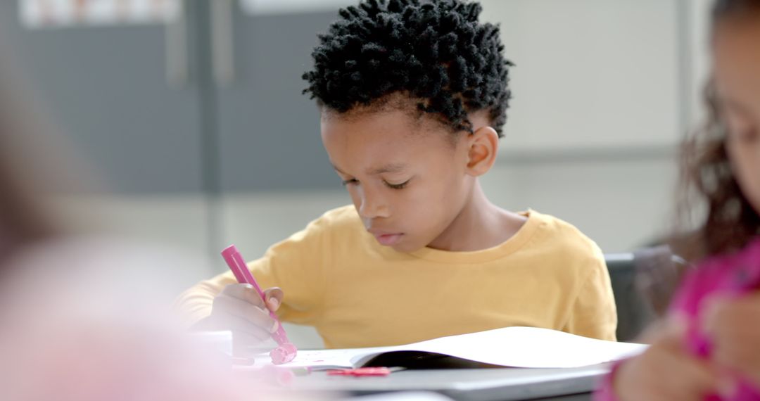 Young Boy Concentrating on Drawing in Classroom Setting