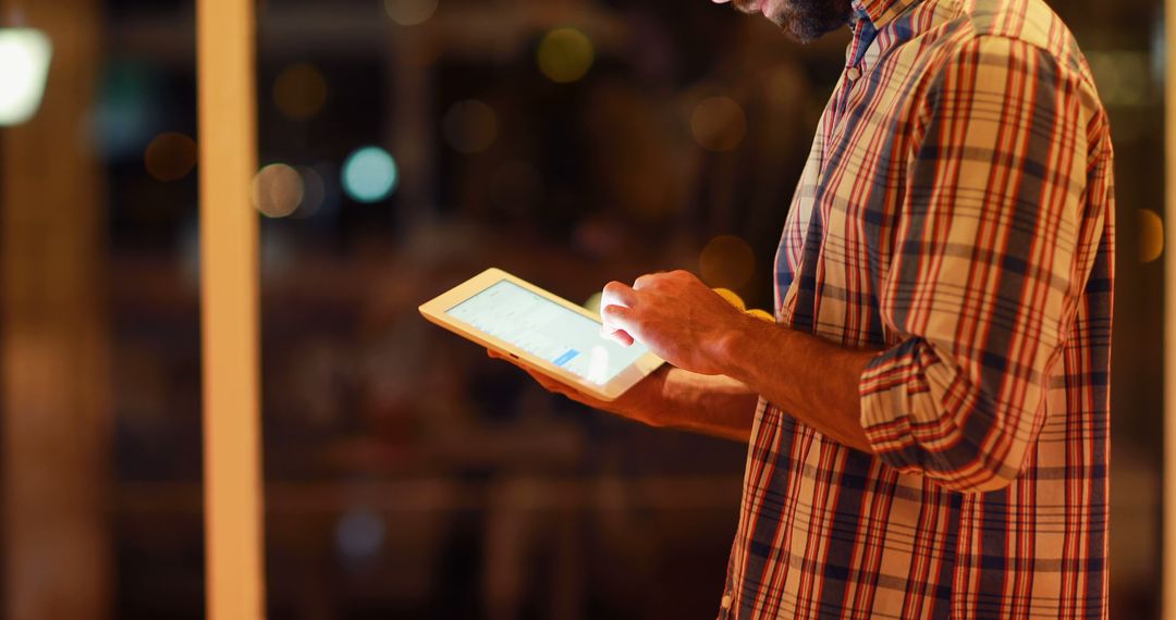 Man using digital tablet at night with bokeh city lights in background - Free Images, Stock Photos and Pictures on Pikwizard.com