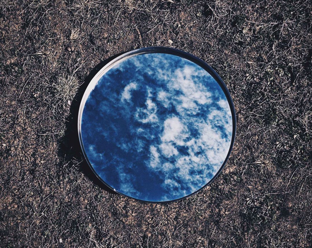 Circular Mirror on Ground Reflecting Blue Sky and Clouds - Free Images, Stock Photos and Pictures on Pikwizard.com