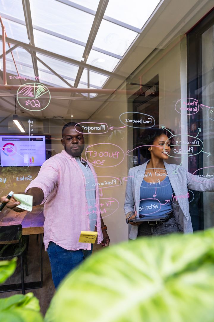 Diverse Colleagues Collaborating on Glass Board with Annotations