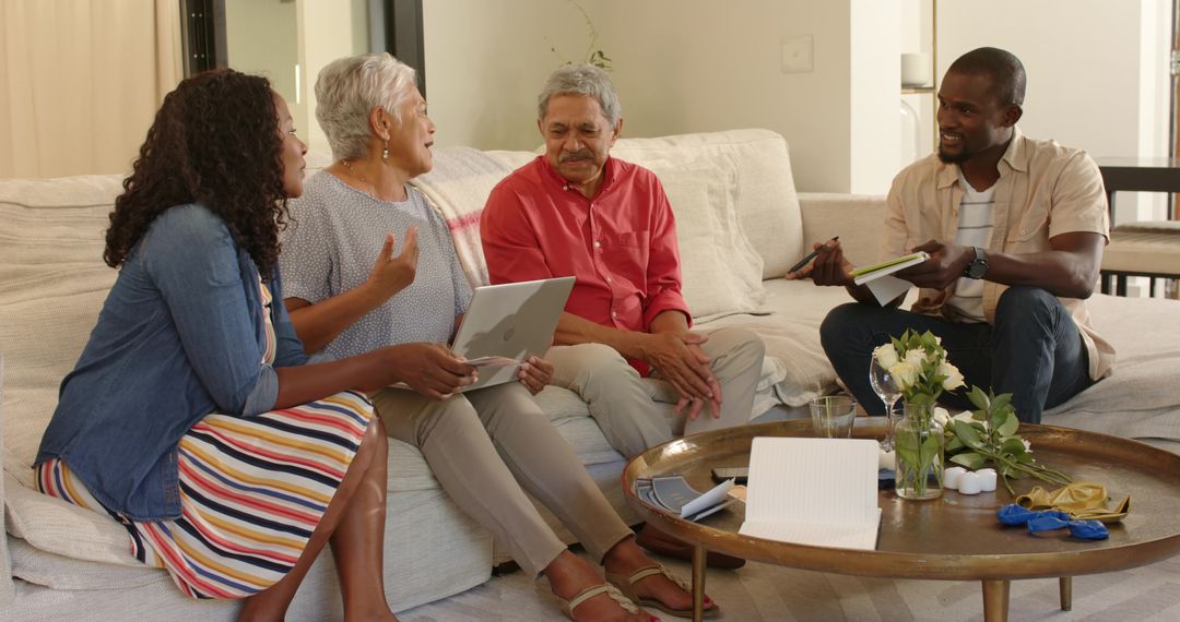 Multigenerational Family Having Meeting on Sofa Using Tablet and Notebook