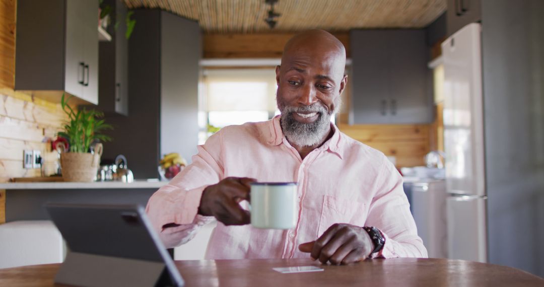 Smiling Man Using Tablet While Drinking Coffee at Home - Free Images, Stock Photos and Pictures on Pikwizard.com