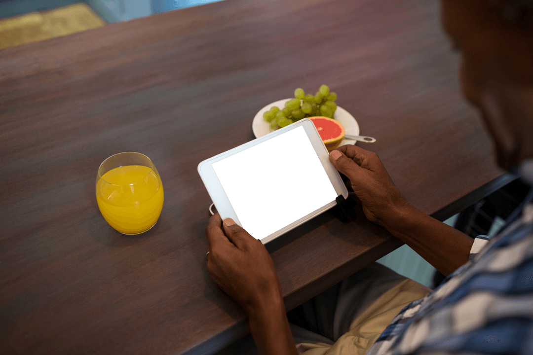 Man Using Tablet at Wooden Table with Transparent Screen and Breakfast
