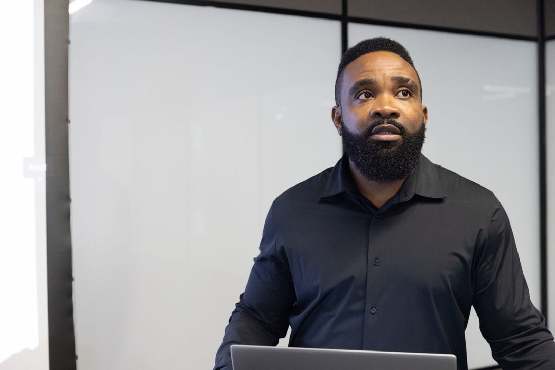 Confident Business Professional Presenting with Laptop and Whiteboard