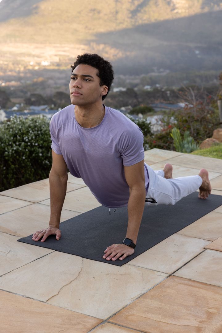 Man Practicing Yoga on Terrace Overlooking Scenic Valley