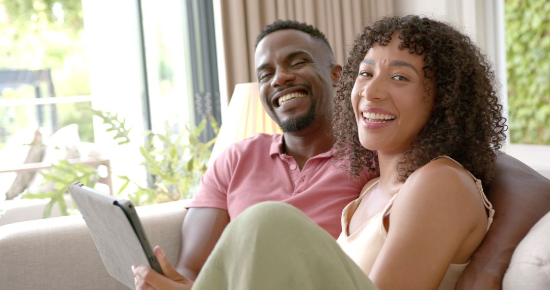 Smiling Couple Relaxing with Tablet on Cozy Sofa