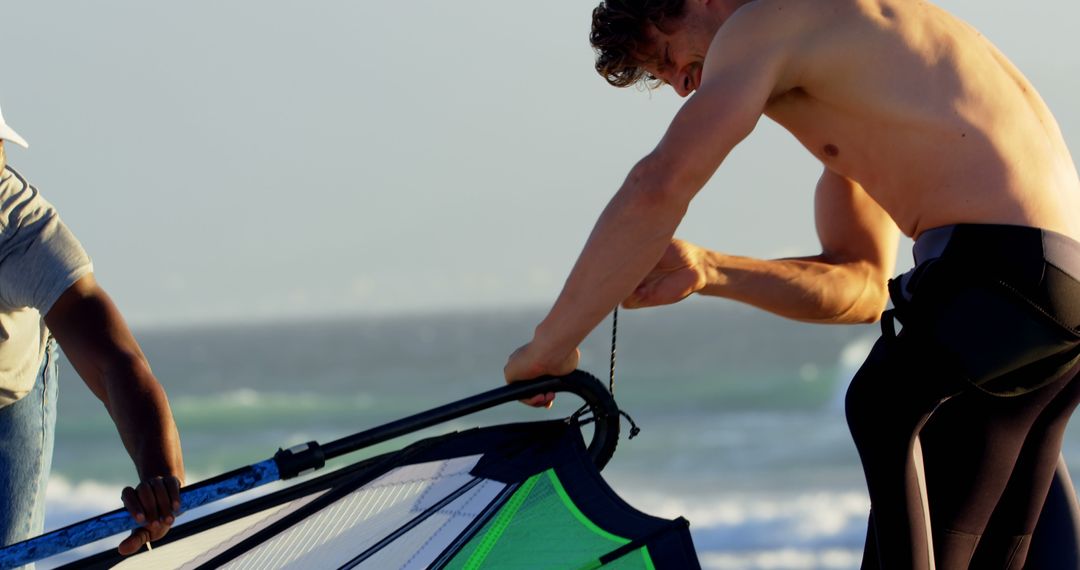 Determined man preparing windsurfing equipment on beach - Free Images, Stock Photos and Pictures on Pikwizard.com