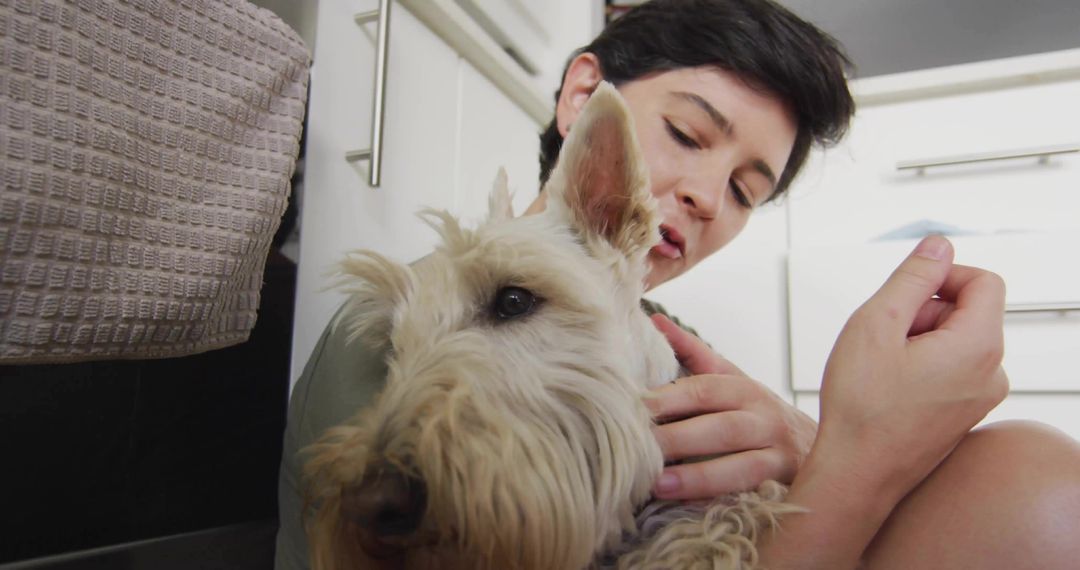 Woman embracing small terrier dog in domestic kitchen scene