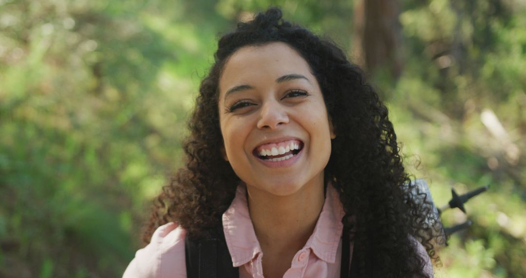 Smiling Young Woman with Curly Hair Enjoying Nature Outdoors - Free Images, Stock Photos and Pictures on Pikwizard.com