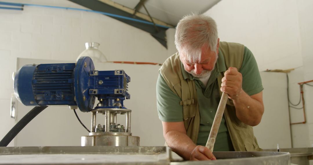 Senior Man Working in Cheese Making Facility Stirring Large Vat - Free Images, Stock Photos and Pictures on Pikwizard.com