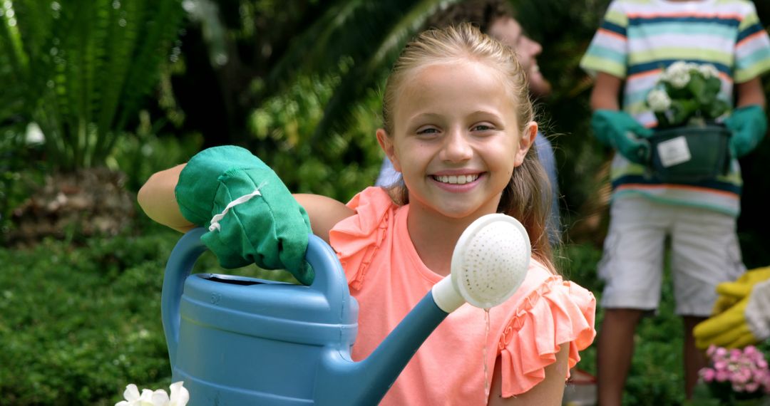 Smiling Girl Watering Plants in Garden with Family - Free Images, Stock Photos and Pictures on Pikwizard.com