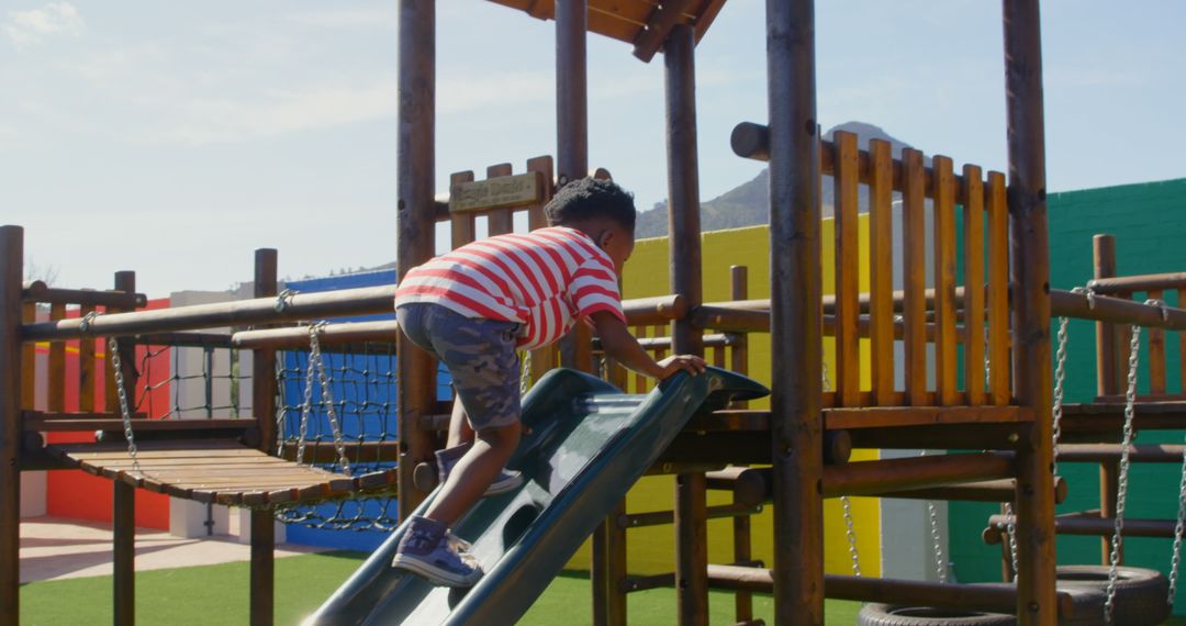 Young Boy Climbing Slide at School Playground on Sunny Day
