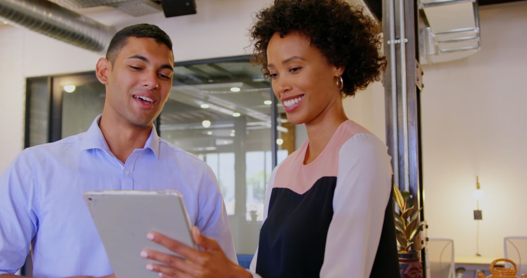 Smiling Colleagues Collaborating on Tablet in Modern Office Environment