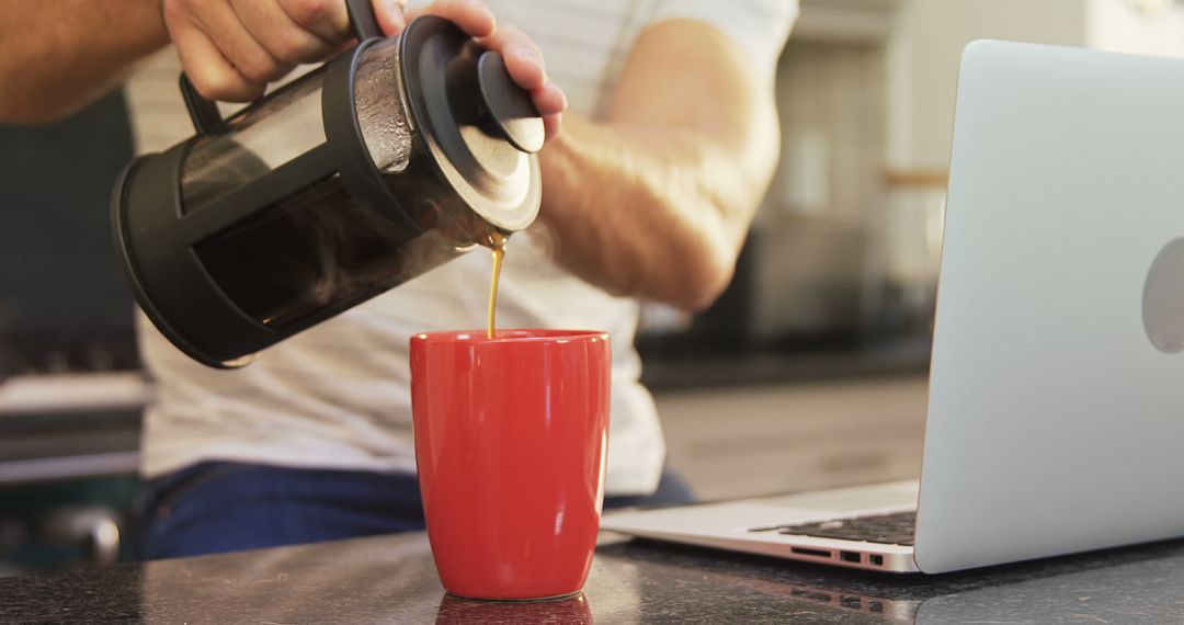 Man pouring coffee from french press into red mug at kitchen counter - Free Images, Stock Photos and Pictures on Pikwizard.com