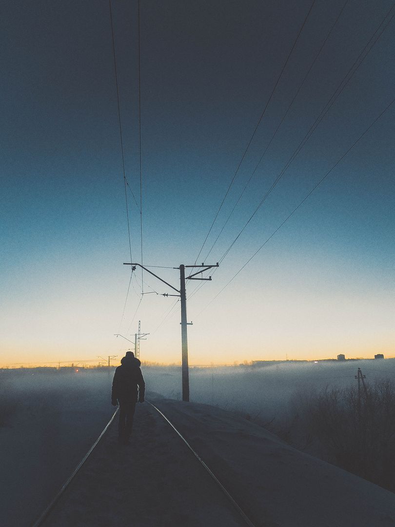 Person Walking Along Misty Railroad Tracks at Dusk - Free Images, Stock Photos and Pictures on Pikwizard.com