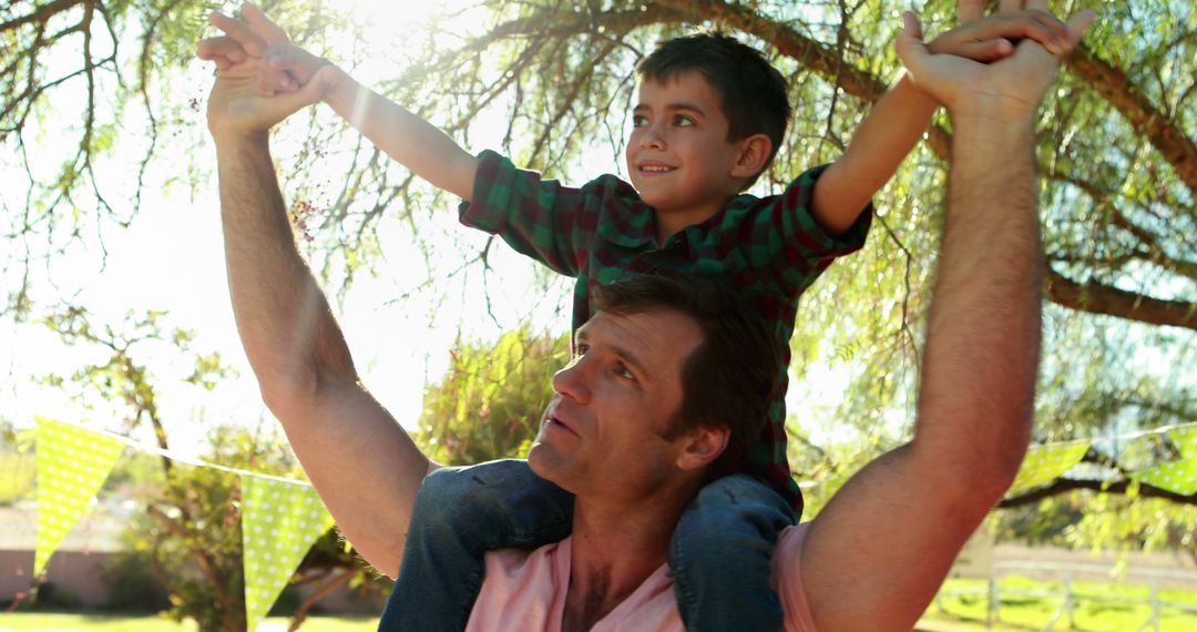 Father Joyfully Carrying Son on His Shoulders in Outdoor Park - Free Images, Stock Photos and Pictures on Pikwizard.com