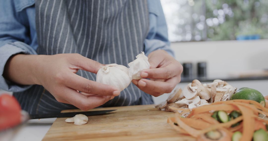 Person Preparing Garlic in Kitchen with Fresh Vegetables - Free Images, Stock Photos and Pictures on Pikwizard.com