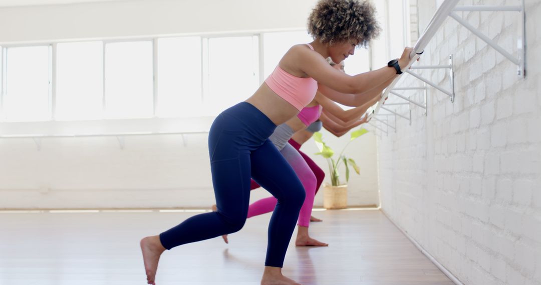Diverse Women Practicing Barre Yoga in Sunlit Studio