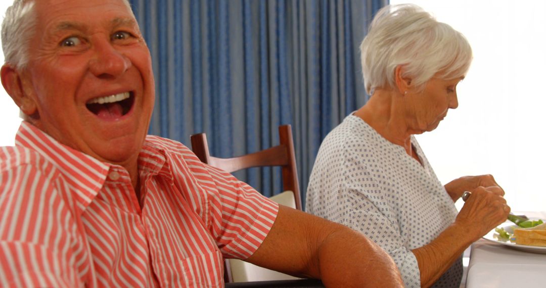 Happy Senior Man Laughing While Elderly Woman Eats Salad at Home - Free Images, Stock Photos and Pictures on Pikwizard.com