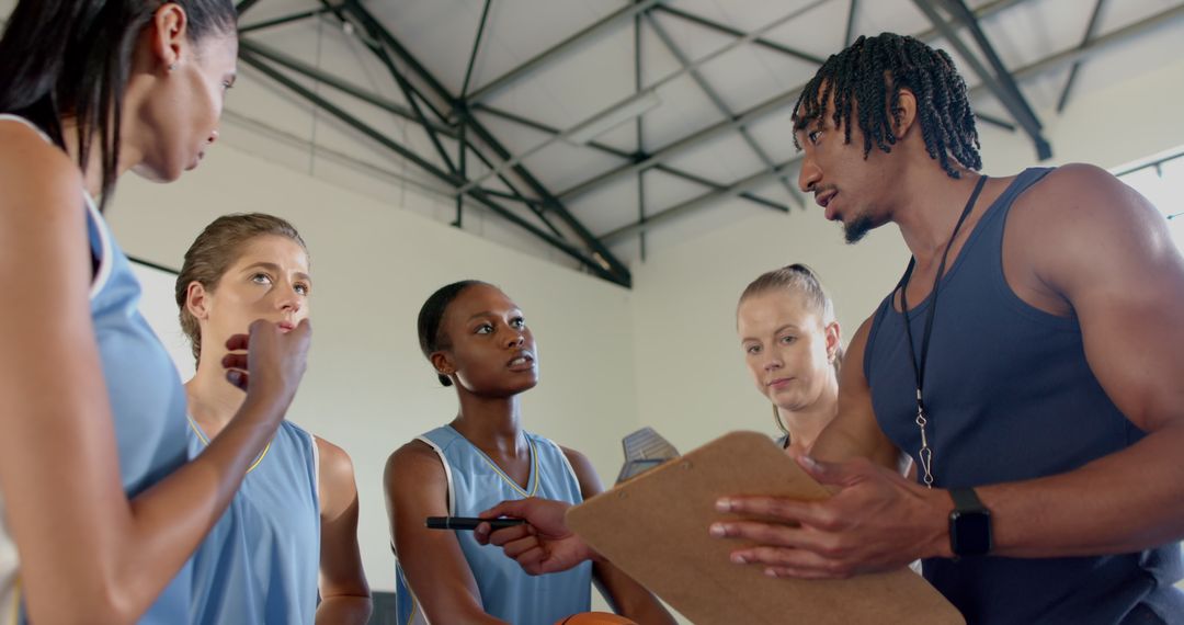 Diverse Basketball Team Training with Coach Using Clipboard