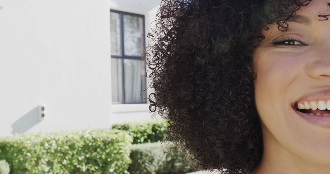 Close-Up of Woman with Curly Hair Smiling Outdoors - Free Images, Stock Photos and Pictures on Pikwizard.com