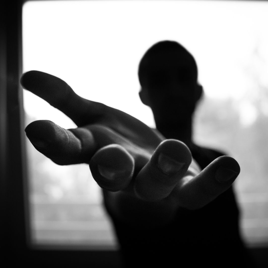 Silhouette of Person Reaching Hand Forward in Black and White