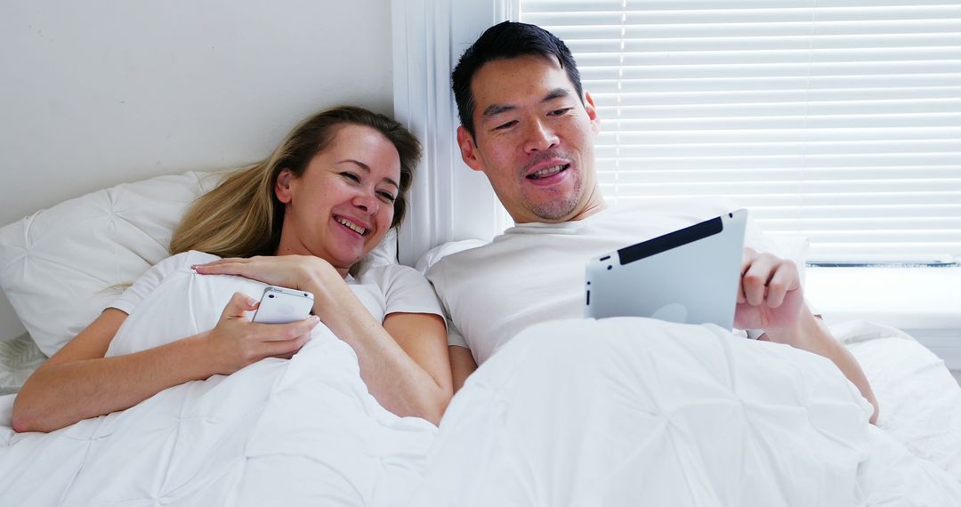 Happy Couple Relaxing with Devices in Bedroom Cozy Atmosphere