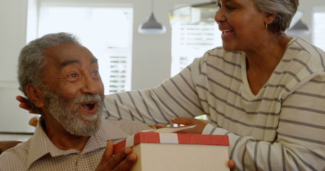 Senior Woman Surprising Husband with Gift at Home, Smiling Together - Free Images, Stock Photos and Pictures on Pikwizard.com