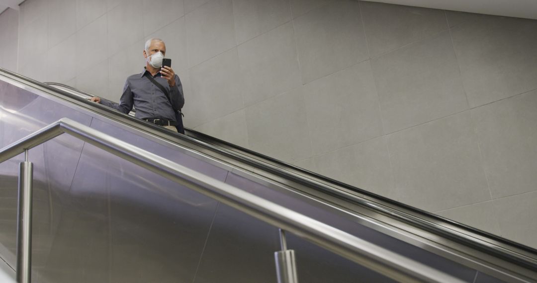 Senior Man Using Smartphone on Escalator Wearing Face Mask - Free Images, Stock Photos and Pictures on Pikwizard.com