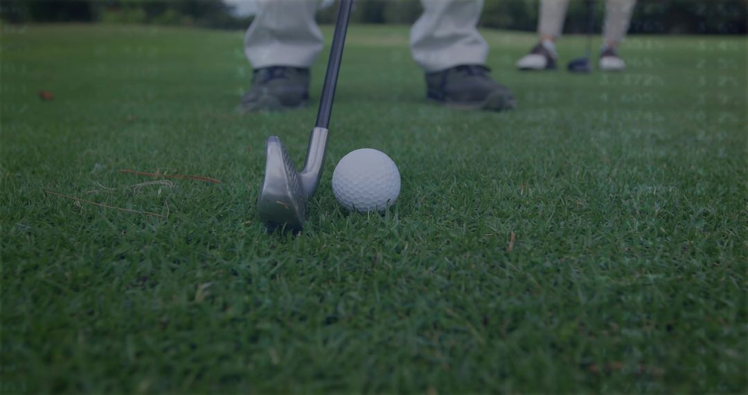 Golf instructor aligning iron behind ball on tee for swing training on lush fairway