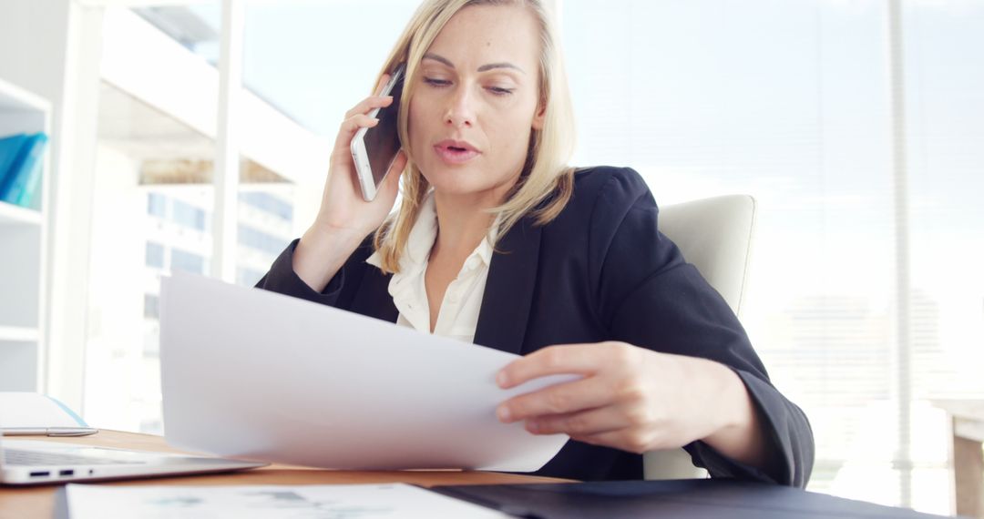 Businesswoman Reviewing Documents and Talking on Phone in Office - Free Images, Stock Photos and Pictures on Pikwizard.com