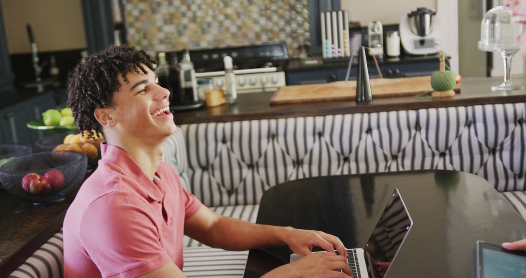 Young Man Laughing While Using Laptop in Modern Kitchen - Free Images, Stock Photos and Pictures on Pikwizard.com