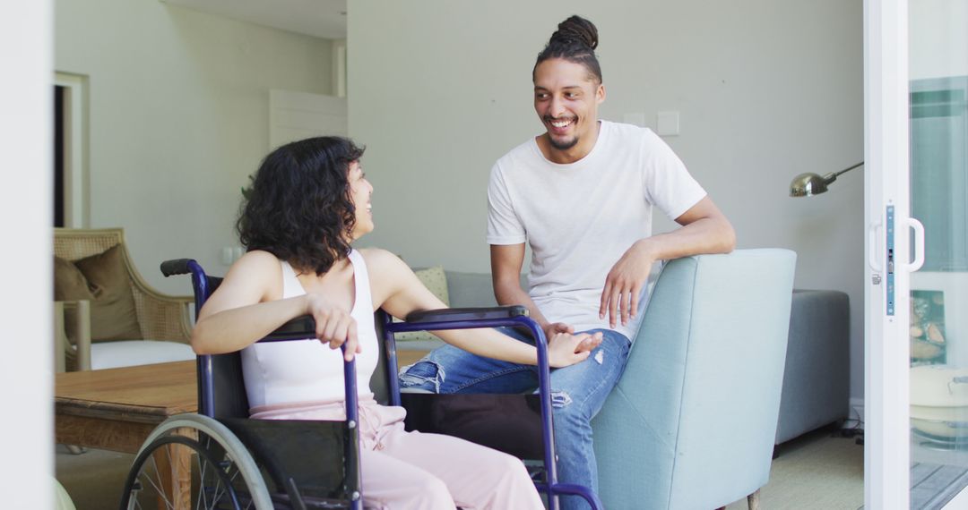 Happy biracial woman in wheelchair and smiling male partner sitting holding hands in living room - Free Images, Stock Photos and Pictures on Pikwizard.com