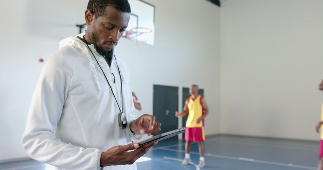 Coach Analyzing Game Data on Tablet in Basketball Gym Facility