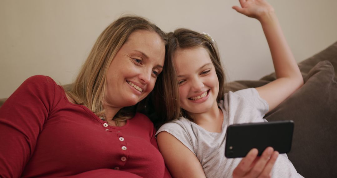 Mother and Daughter Smiling While Watching Smartphone Together on Sofa - Free Images, Stock Photos and Pictures on Pikwizard.com