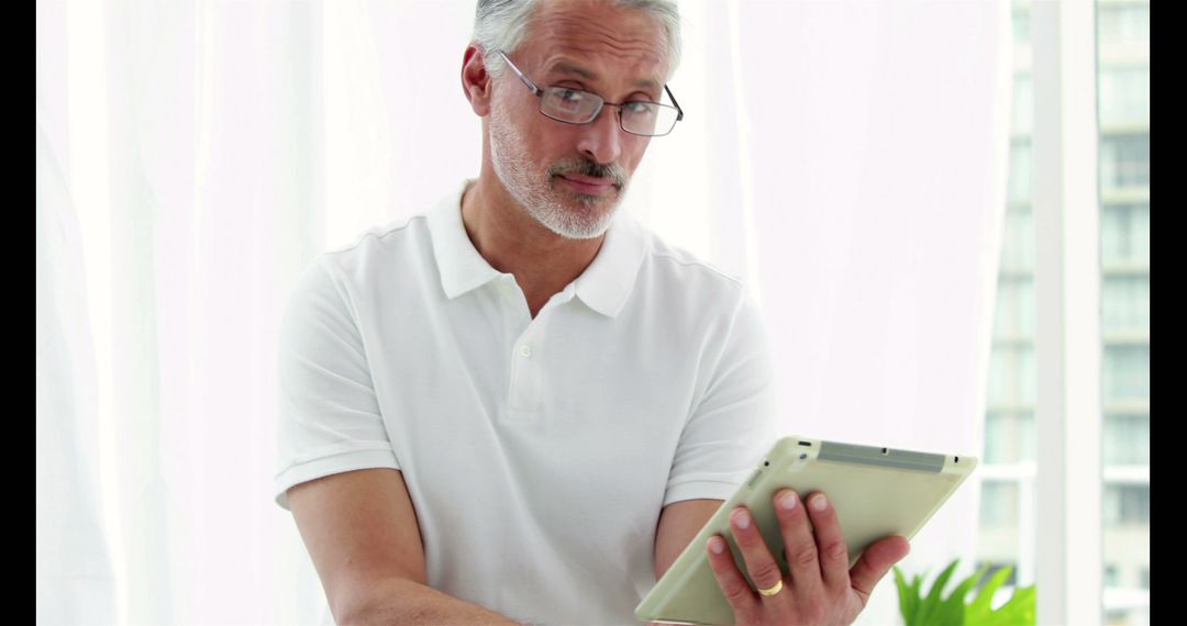 Senior Man Using Tablet with Skeptical Expression While Standing - Free Images, Stock Photos and Pictures on Pikwizard.com