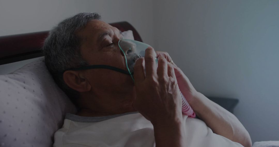 Senior Man Using Oxygen Mask while Resting on Bed