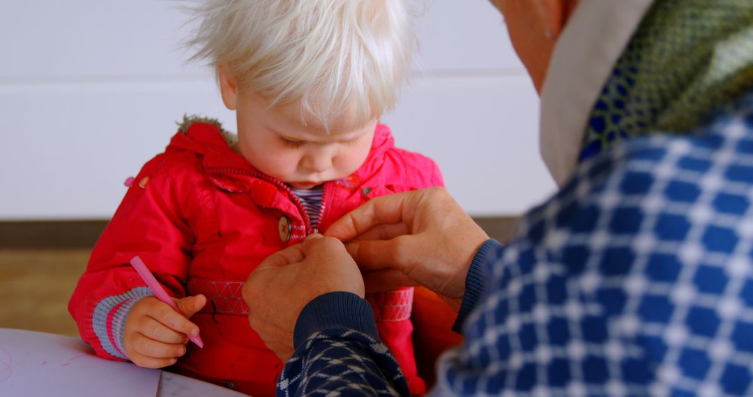 Father Assisting Daughter in Red Jacket at Home Table
