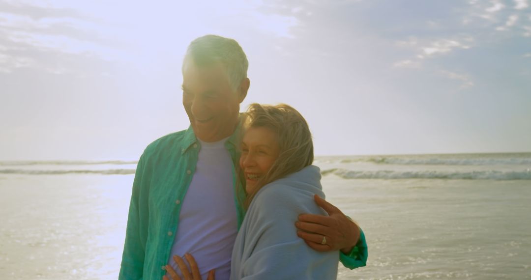 Happy Senior Couple Embracing at Beach During Sunset