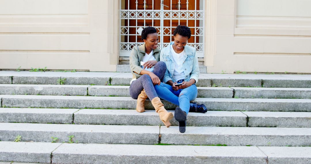 Twin Sisters Relaxing on Outdoor Steps with Smartphone
