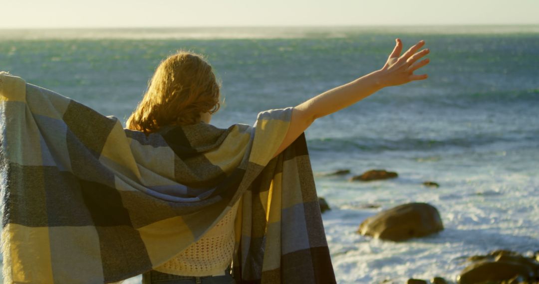 Joyful Woman Embracing Ocean Breeze at Rocky Beach Sunset - Free Images, Stock Photos and Pictures on Pikwizard.com