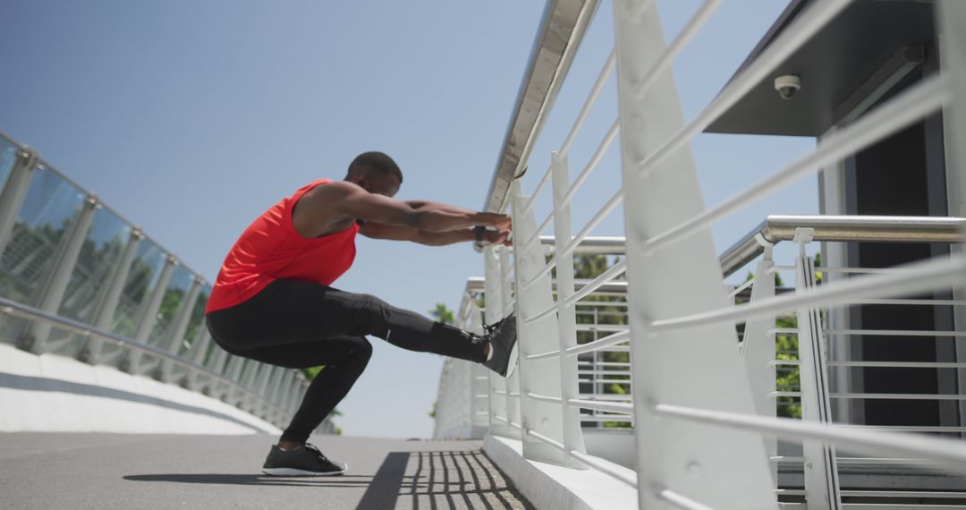 Man in Red Tank Top Stretching Legs on Modern Bridge - Free Images, Stock Photos and Pictures on Pikwizard.com