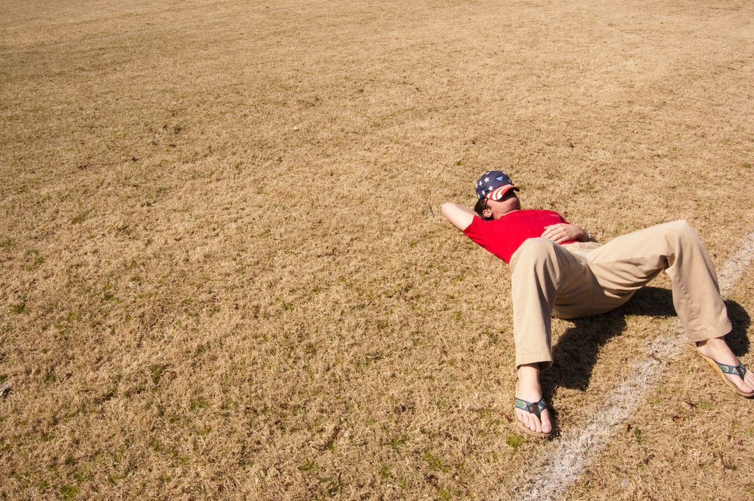 Man Relaxing on Dry Grass Field in Bright Sunlight - Free Images, Stock Photos and Pictures on Pikwizard.com
