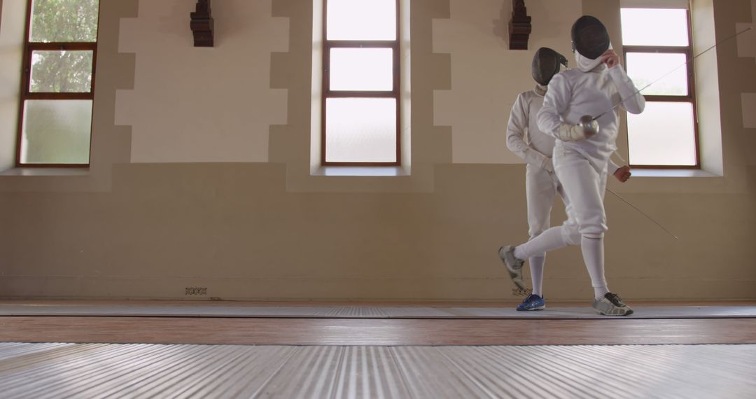 Two fencers practicing in a gym with natural light - Free Images, Stock Photos and Pictures on Pikwizard.com